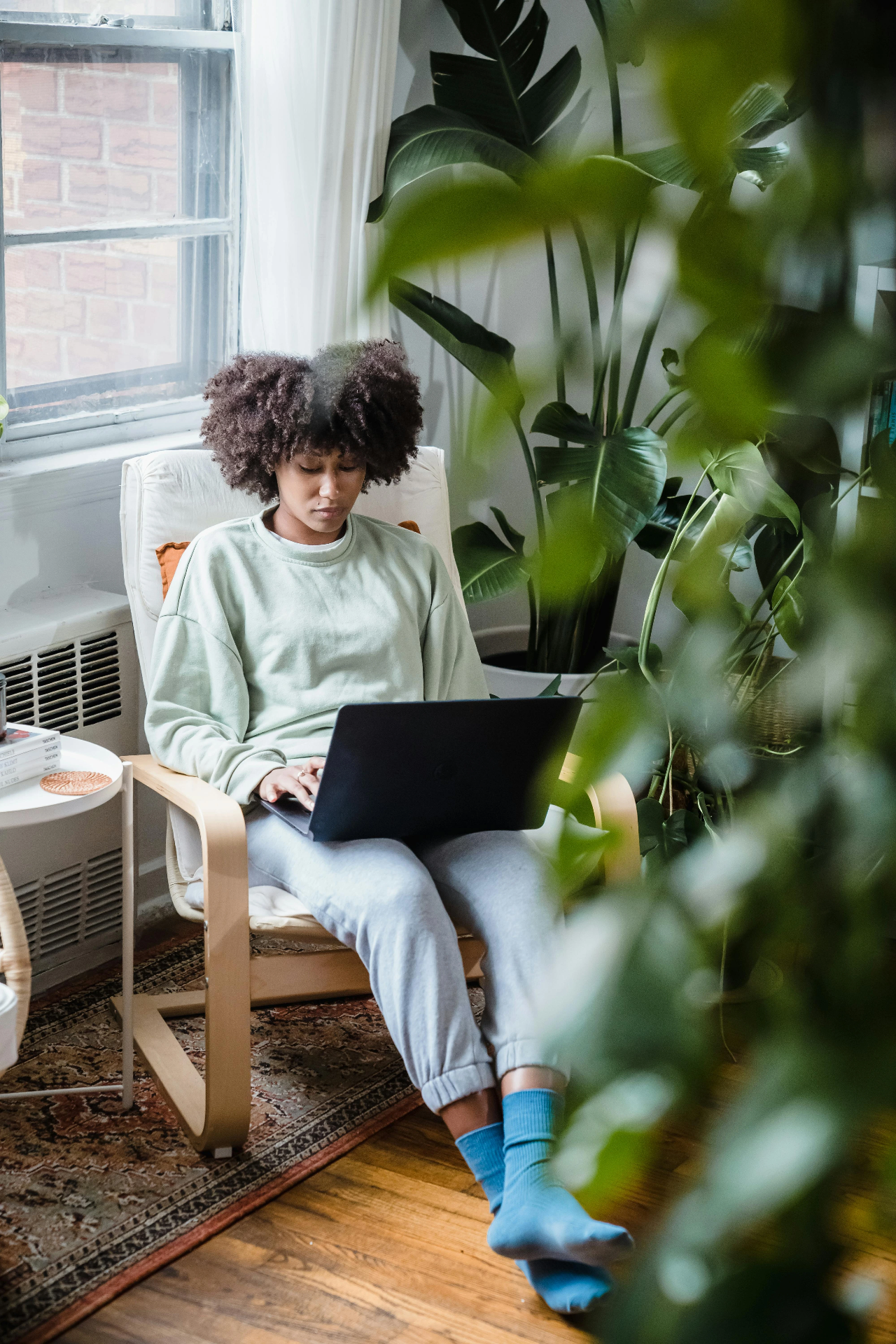 Femme en télétravail seule dans un salon lumineux avec son ordinateur portable.