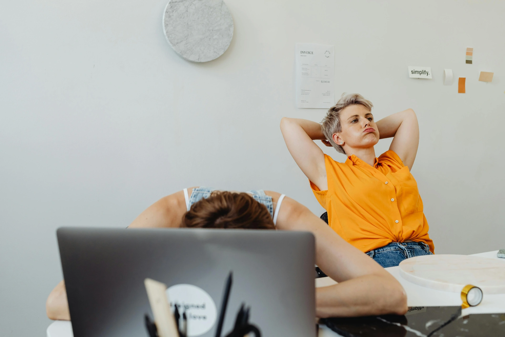 Deux femmes en télétravail fatiguées dans un espace de travail, illustrant la lassitude du travail isolé.