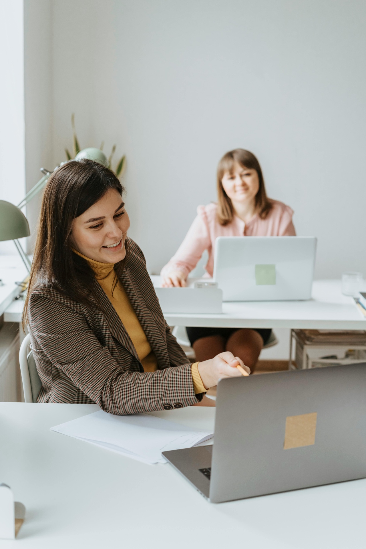 Deux collègues dans un bureau partageant un moment de travail sur ordinateur.